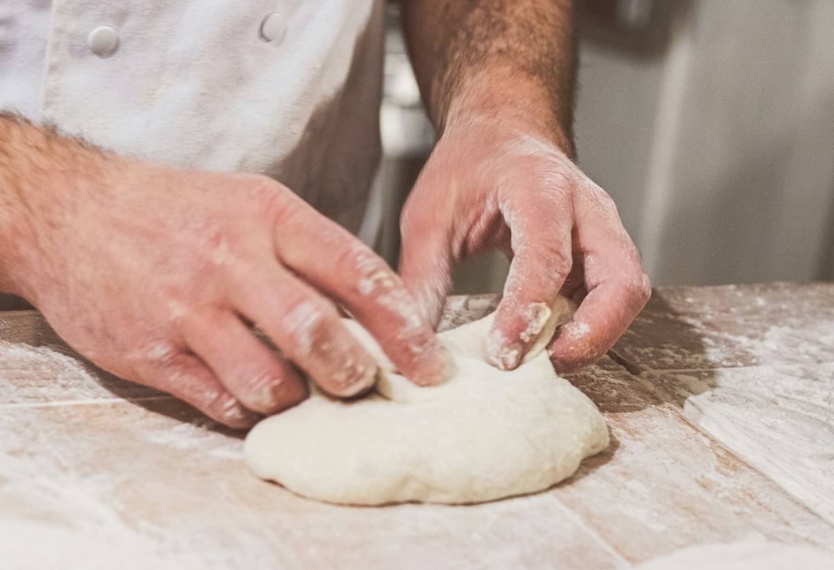 Close-up of bread machine kneading bread using dough hook with golden dough swirling around the hook
