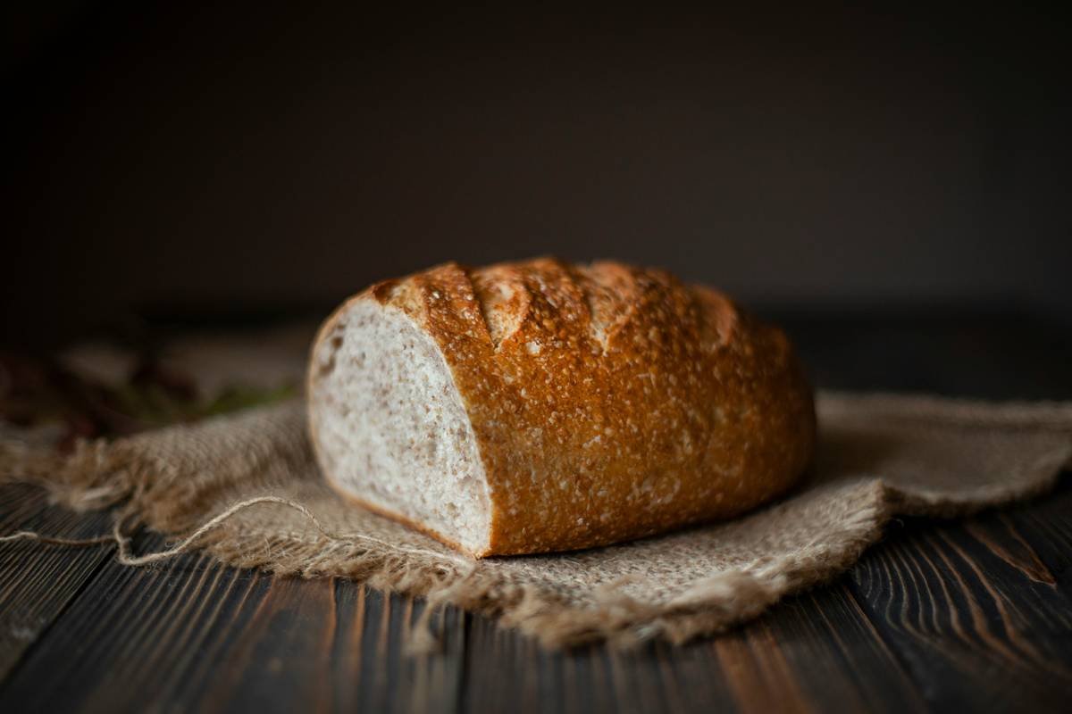 baking bread for beginners recipes showing a golden loaf fresh from a bread machine on a wooden counter